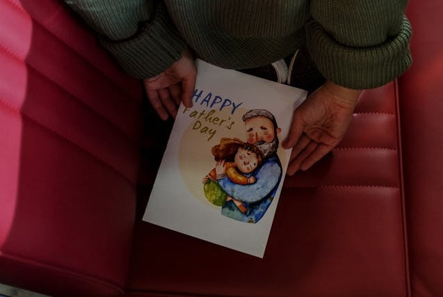a girl holding a Father’s Day gift and card behind her back