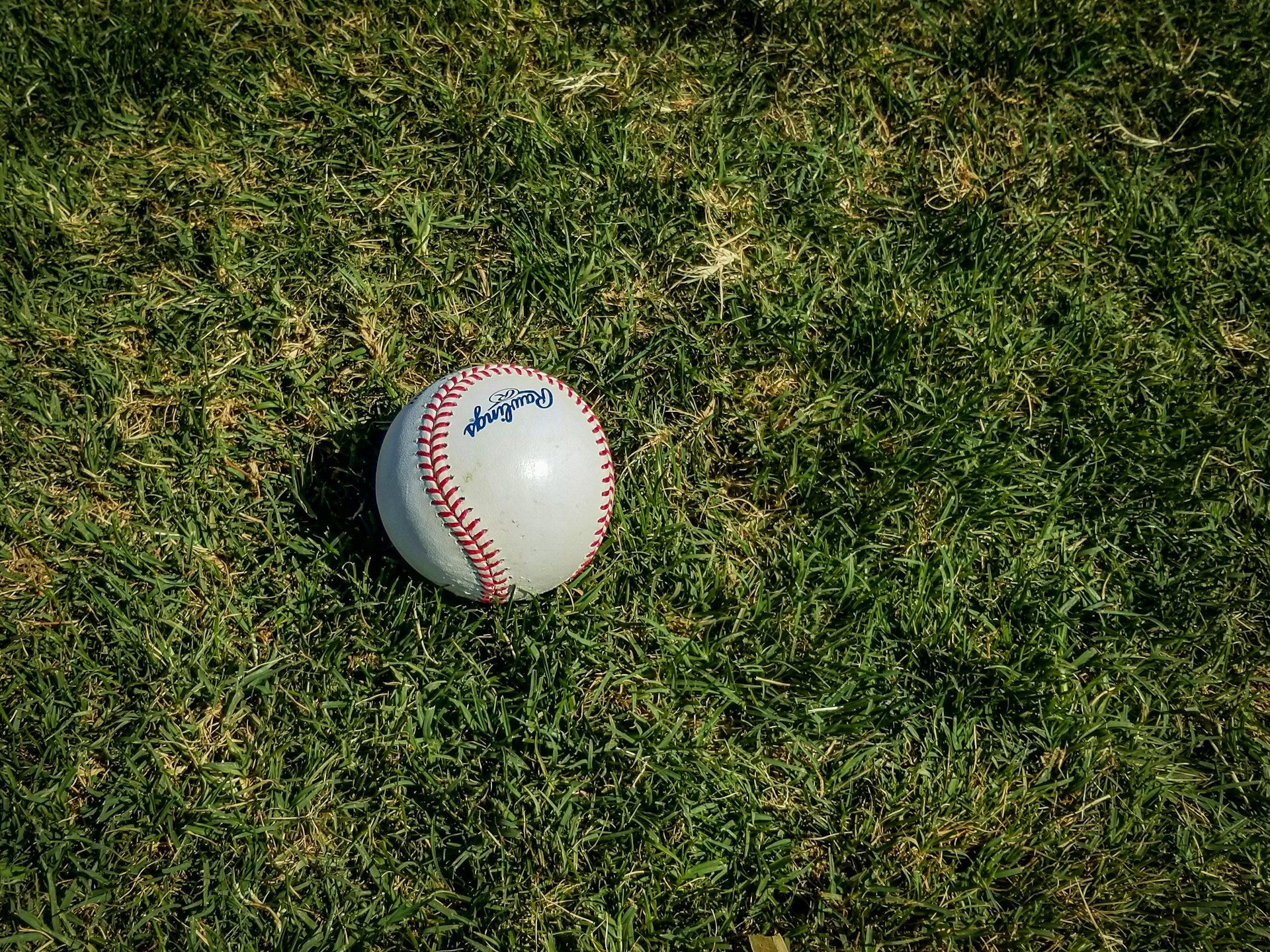 White and red baseball lying on grass