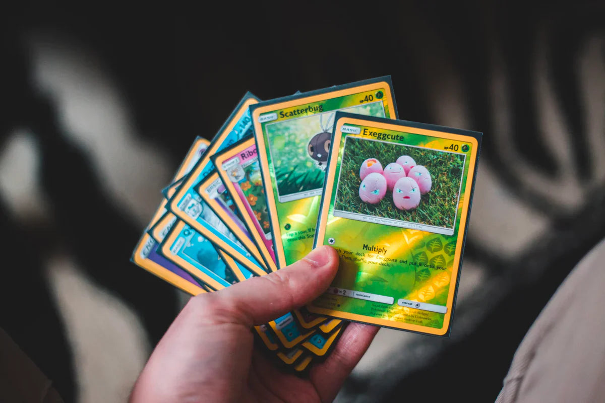 Hand holding green and blue Pokémon cards
