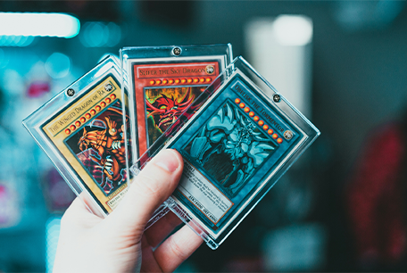 a hand holding three Yu-Gi-Oh cards